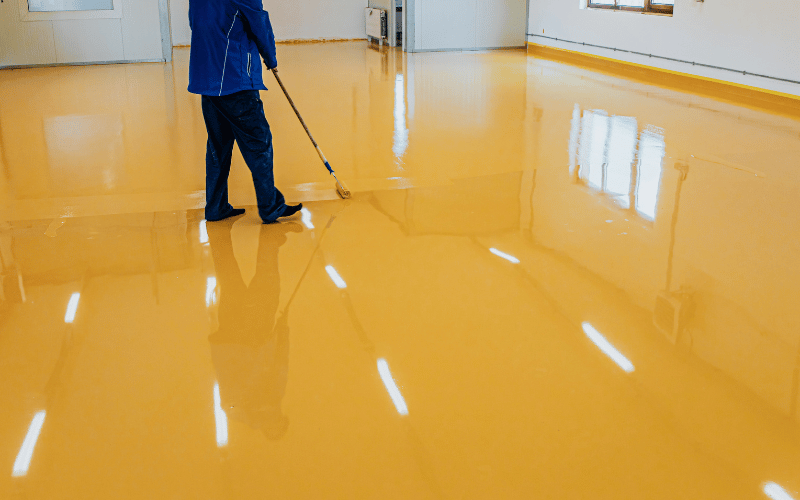 Worker putting down new yellow polyurea floor